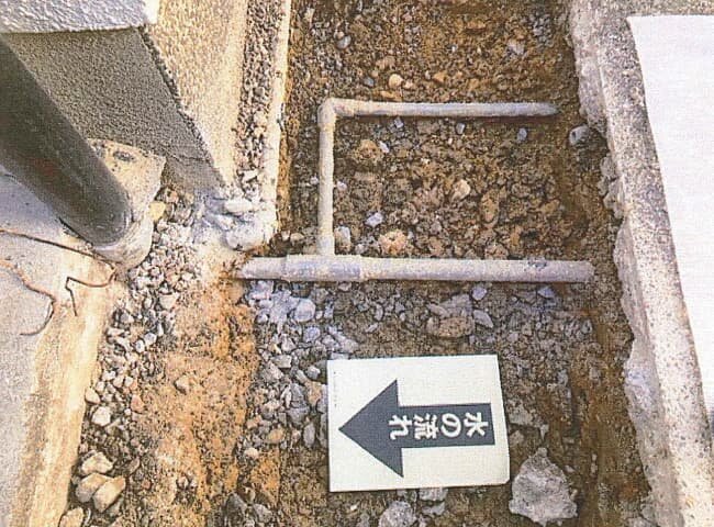 コンクリートをはつり、地中から給水配管が現れた様子